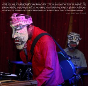 Picture of two people playing music while wearing masks.