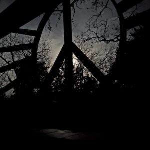 Large peace sign with woods behind it.