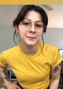Woman with glasses and nose ring wearing yellow shirt.