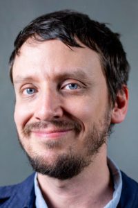 Man with blue eyes and brown hair smiling at camera.